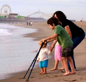 Child with crutches on the beach